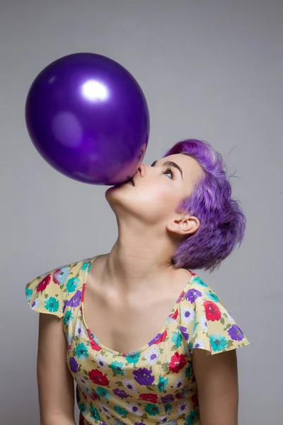 Violeta de cabelos curtos menina segurando um balão com a boca, olha — Fotografia de Stock