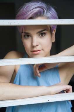 Bir fenc arkasında güzel bir mor kısa saçlı kadın