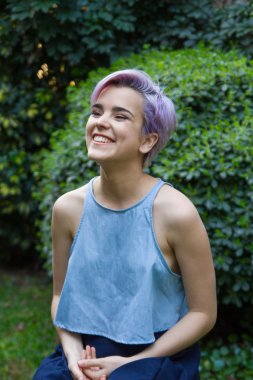 Menekşe kısa saçlı kadın gülüyor, açık havada oturun