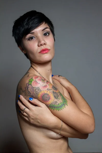 Гола короткошерста брюнетка обнімає себе татуюванням на — стокове фото