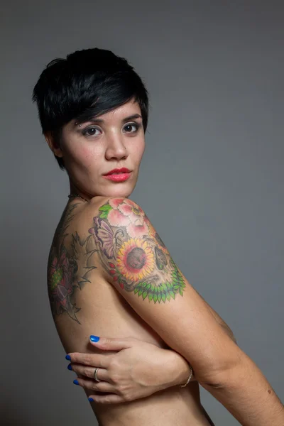 Голая брюнетка с короткой стрижкой, покрывающая себя татуировкой — стоковое фото