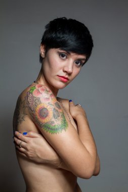 Kendini sarılma ve onu kapsayan çıplak kısa saçlı esmer kadın