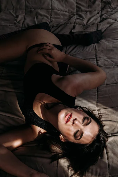 Szexi nő feküdt az ágyban, a szeme bezárása Stock Kép