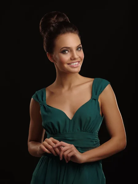 Joven hermosa chica sonriente en el vestido verde con el pelo recogido y maquillaje expresivo sobre el fondo negro — Foto de Stock