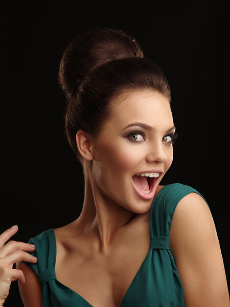 Портрет молодой удивленной красивой девушки с собранными волосами и выразительным макияжем на черном фоне, говорящим вау
