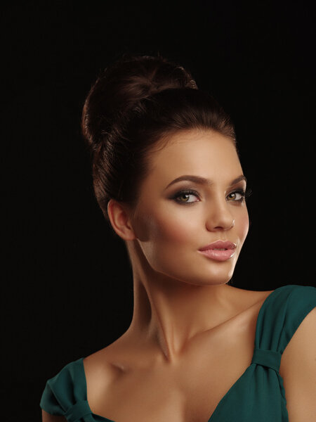 Портрет молодой красивой девушки с собранными волосами и выразительным макияжем на черном фоне
