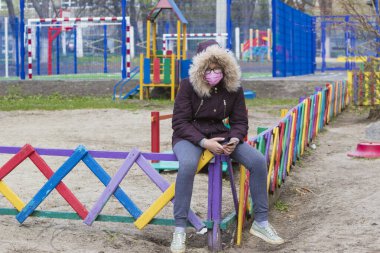 Çocuk parkında maskeli genç bir kız.