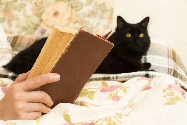 Kitabı ve siyah kedisi olan bir kadın.