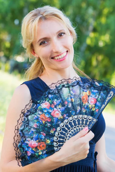 Beautiful portrait of a young woman with a fan in nature