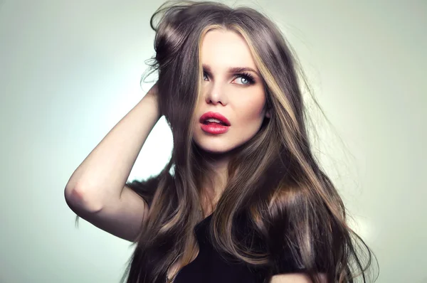 Woman model with great hair and makeup, red lips and deep blue eyes - posing at studio in the softbox and light flashes.