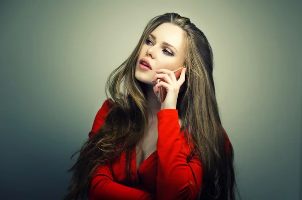 Mujer en vestido rojo con cara linda perfecta hablando en el teléfono inteligente . — Foto de Stock