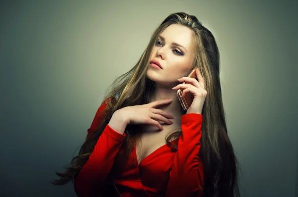 Mujer en vestido rojo con cara linda perfecta hablando en el teléfono inteligente . — Foto de Stock