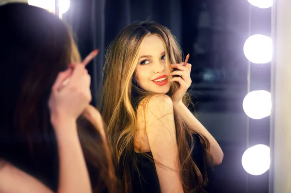 Jeune femme caucasienne regardant dans le miroir de maquillage à elle-même et profiter de son temps . — Photo