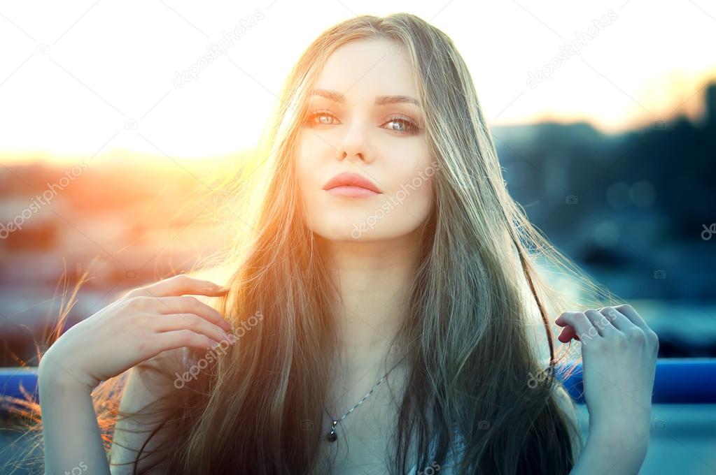 Woman with sensual lips posing at roof at the end of bright sunset.