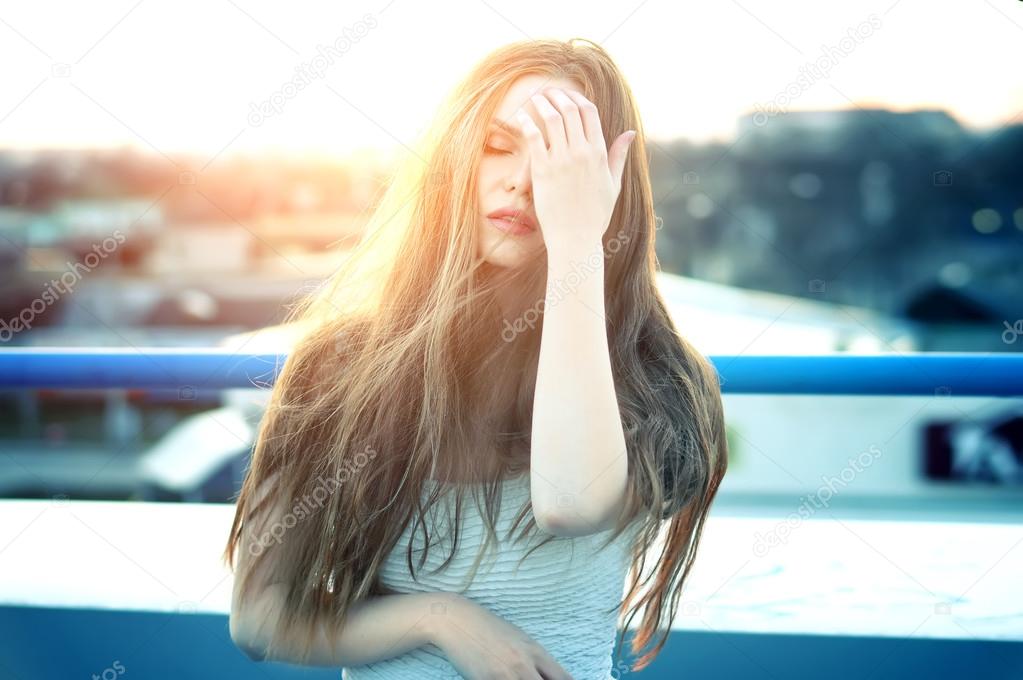 Pretty sexy woman with sensual lips posing at roof at the end of bright sunset.