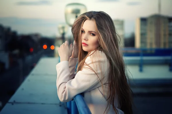 Einsame junge hübsche Mädchen steht auf dem Dach der Stadt im Sonnenuntergang. — Stockfoto