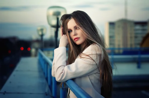 Chica bonita joven y solitaria de pie en el techo de la ciudad al atardecer . — Foto de Stock