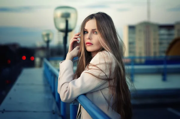 Chica bonita joven y solitaria de pie en el techo de la ciudad al atardecer . — Foto de Stock