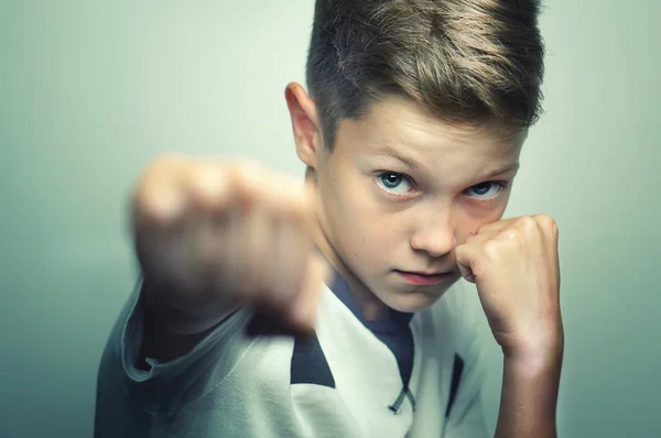 Angry child boy in white t-shirt training box punch.