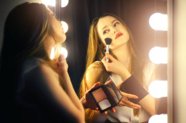 seksi genç kadın kendini aynaya bakıyor ve kozmetik fırça'yı kullanın