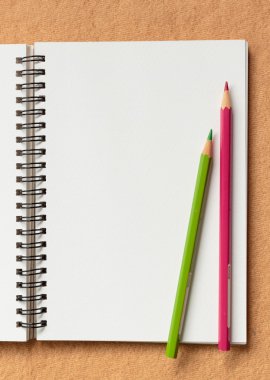 kahverengi zemin üzerine defter ve renk kalemler