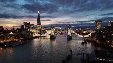 London. UK- October 07. 2025. A drone aerial Thames River approach to Tower Bridge during blue hour.