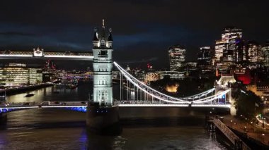 London. UK- October 07. 2025. A aerial close up footage of the iconic Tower Bridge at night with the drone flying from right to left across the River Thames.