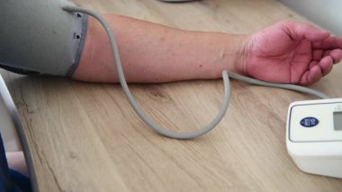 Kan basıncını ölçmek için tansiyon monitörünün enflasyon manşetini çıkartan birinin yakın çekimi..
