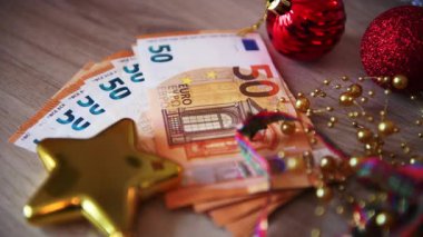 Masasında 50 Euro 'luk banknotlar ve Noel süslemeleri olan bir Avrupa Noel konsepti..