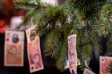 Bir Noel ağacına asılı Sterling banknotlarının yakın plan resmi oturma odasındaki süsler gibi. Noel konseptinin bedeli.