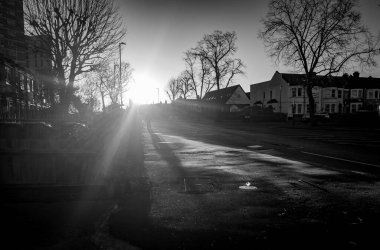 Güneşli bir kış gününde, Londra 'nın banliyö caddesinin sokak manzarası. Güneş ufuktan zar zor yükselirken. Kış güneşi siyah ve beyaz.