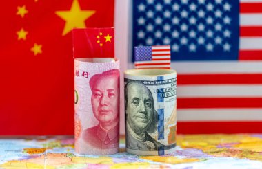Bir rulo Amerikan doları ve Çin Yuan banknotlarını Çin ve Amerikan ulusal bayraklarının olduğu bir dünya haritasına yakın plan. Çin, ABD ekonomik, mali, para birimi çatışması kavramı.