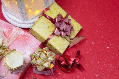 Noel ve Yeni Yıl kompozisyonu. Kırmızı arka planda süsleri, hediyeleri ve parlak fiyonkları olan şenlikli parlayan bir fener.