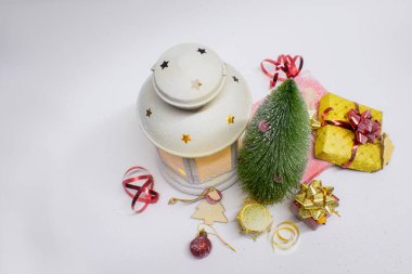 Noel ve Yeni Yıl kompozisyonu. Noel ağacı, süslemeler, hediyeler ve beyaz arka planda parlak fiyonklar olan parlak bir lamba.