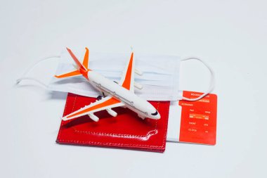 Seyahat zamanı. Covid-19 Coronavirus salgını sırasında güvenli dinlenme kavramı. Tıbbi maskeli, pasaportlu ve uçağa bilet almış bir uçak.