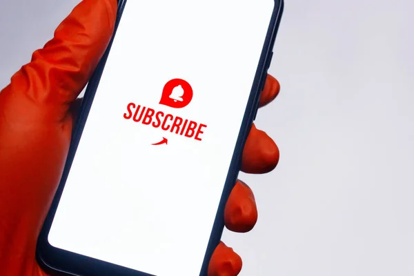 Subscribe to the Internet channel on the smartphone display. A man in medical gloves holds a phone in his hand close-up on a white background