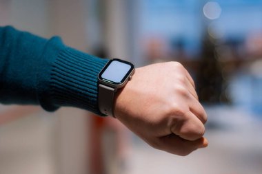 Elinde beyaz ekran maketi olan akıllı bir adam. Adamın biri alışveriş merkezinin arka planında spor aleti kullanıyor.