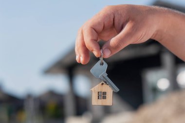 Evin anahtarlarını elinde tutan adam, konut binalarının arka planına karşı. Konut satın alma ve kiralama kavramı