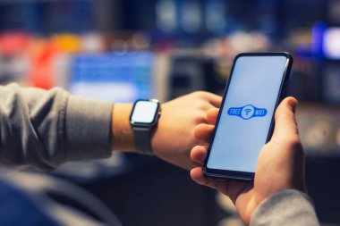 Adamın elinde kablosuz ağ ikonu ve akıllı saati olan akıllı bir telefon var.