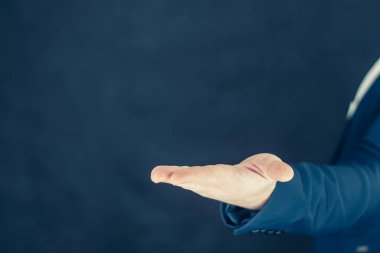 Gömlekli ve mavi ceketli bir işadamı elleriyle el hareketlerini gösteriyor.