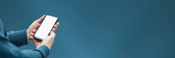 Adam yeşil arka planda beyaz ekranlı akıllı telefonun bir kopyasını tutuyor.