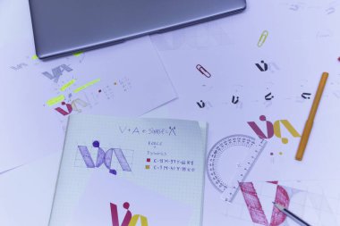 Kağıda basılmış logonun çizimleri ve çizimleri. Logo tasarımının stüdyoda dizüstü bilgisayarlı bir masada geliştirilmesi