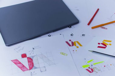 Dizüstü bilgisayarlı Grafik Tasarımcı 'nın yaratıcı iş yeri. Şirket için bir logo geliştirme. Bir sanat stüdyosundaki çizimler ve eskizler.