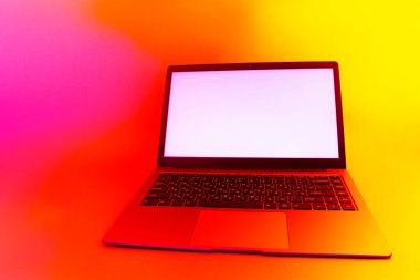 Beyaz ekranlı ince modern dizüstü bilgisayar parlak, kırmızı yaratıcı ışığa karşı ayarlandı