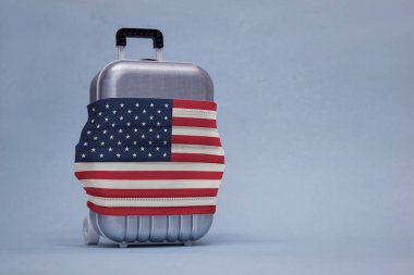 Seyahat zamanı. Covid-19 Coronavirus salgını sırasında güvenli dinlenme kavramı. Tıbbi maske ve Amerikan bayrağıyla seyahat çantası.
