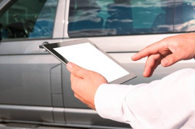 Teknolojiyi geliştir. Beyaz gömlekli bir iş adamı arka planda beyaz ekranlı bir tablet tutuyor.