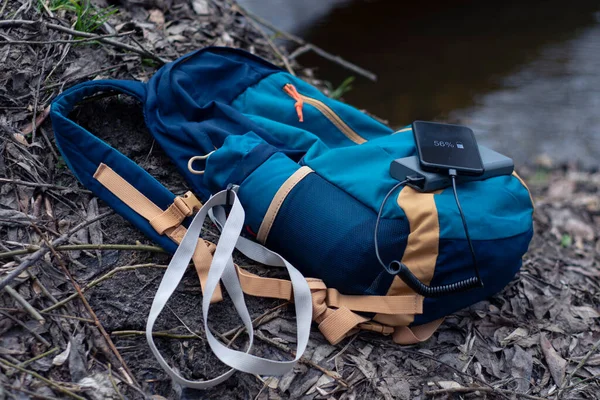 Smartphone is charged using a portable charger. Power Bank charges the phone outdoors with a backpack for tourism in nature