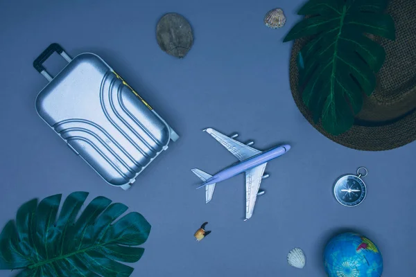 Travel by plane concept. Suitcase for tourism and recreation with hat and plane on a light background with seashells and compass