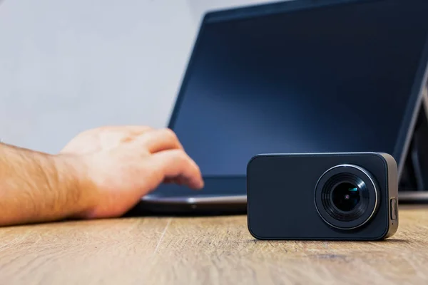 Action Camera on the table against the background of a man working at a laptop