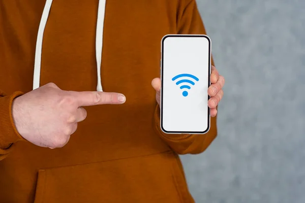 Man hand holding silver smartphone isolated on light background. Phone mockup with white screen and wi-fi icon